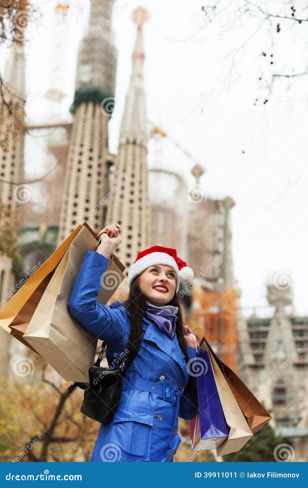 Uśmiechnięta dziewczyna z zakupami w Barcelona. Uśmiechnięta dziewczyna z zakupami przeciw Sagrada familia podczas Bożenarodzeniowych sprzedaży w Barcelona