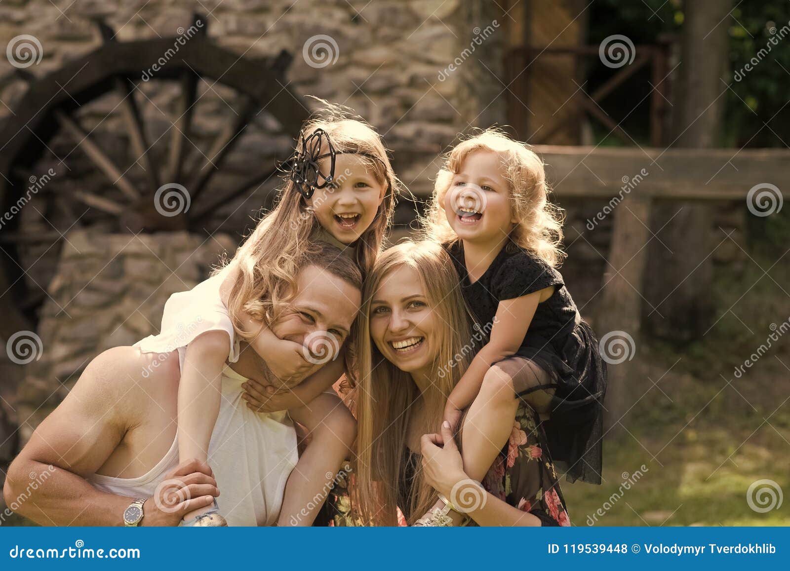 Vacances d'été, aventure, découverte, concept d'envie de voyager Enfance heureux, famille, amour Moulin en pierre de visite d'enfants et de parents vieux Mères, jour de pères Les filles s'asseyent sur des épaules de femmes et d'hommes