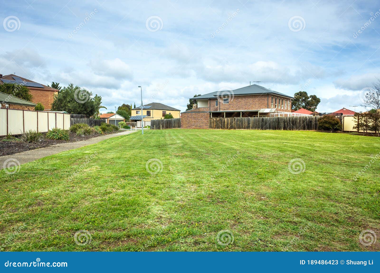 A Vacant Land with Green Grass/lawn Surrounded by Suburban Houses in a Melbourne`s Suburb. VIC Australia. Stock - of buildings, mortgage: