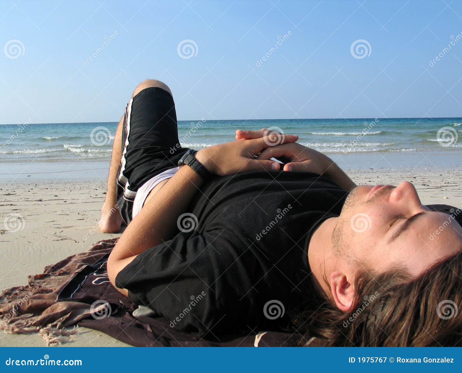 Vacanza di estate - uomo sulla spiaggia. Ritratto di un uomo che cattura sunbath alla spiaggia