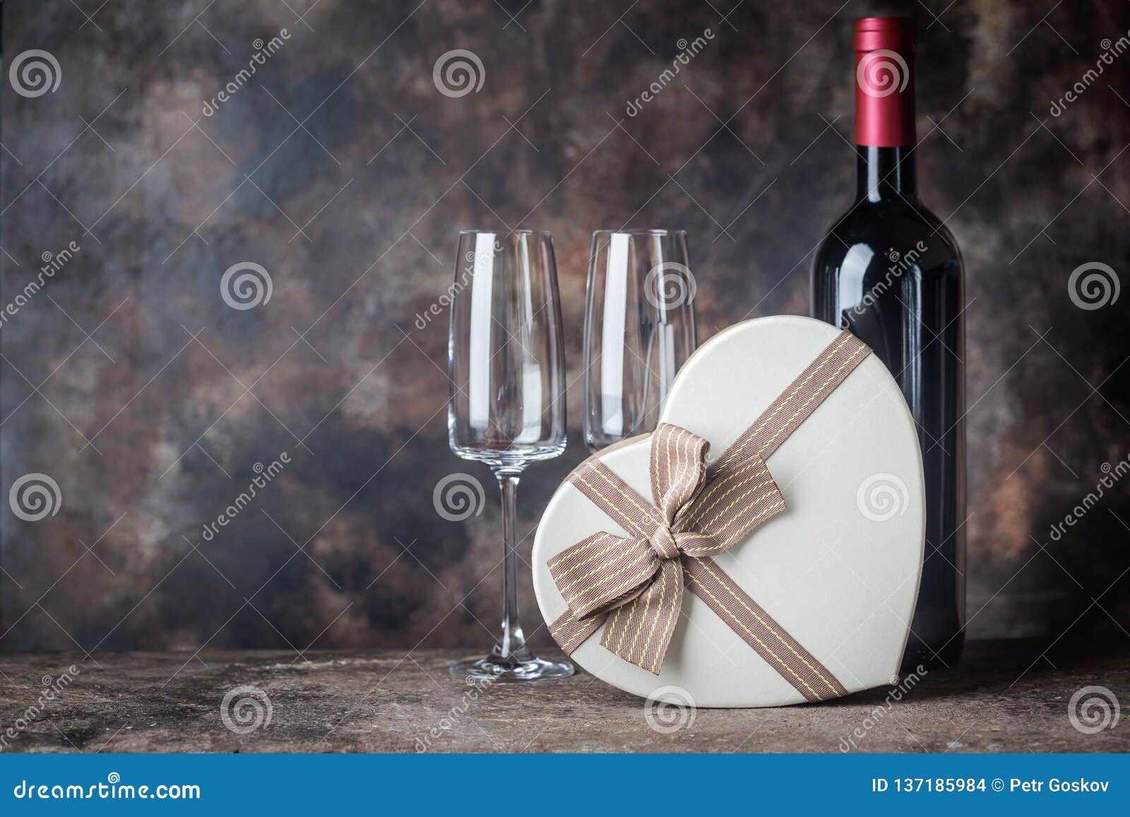 Valentinsgruß `s Tagesgrußkarte. Valentinstaggrußkarte mit Herzen formte Geschenkbox und Rotwein mit Gläsern auf dunklem Hintergrund