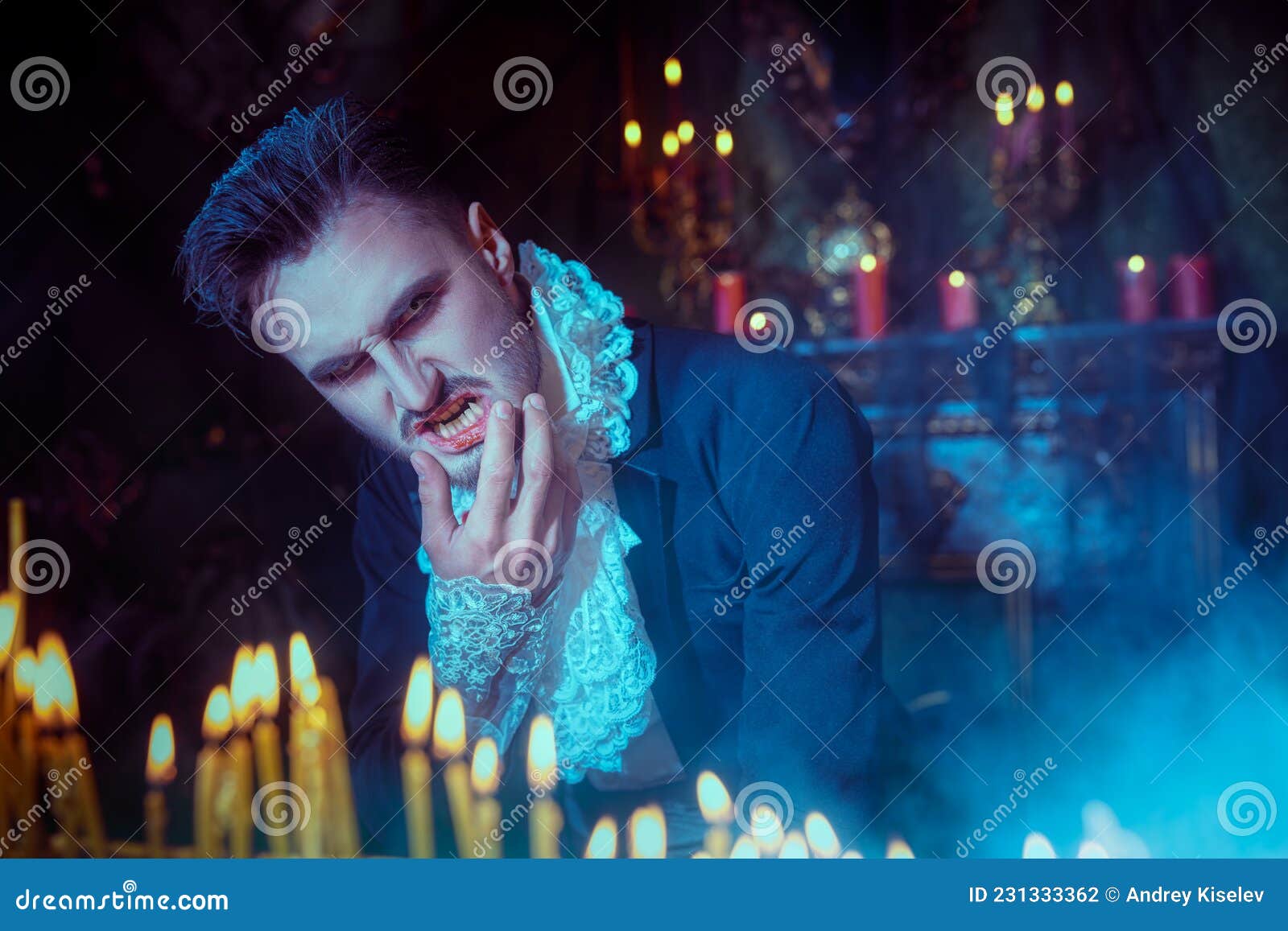 Homem bonito vestido com uma fantasia de drácula para o halloween. vampiro  atraente com velas estende a mão para frente