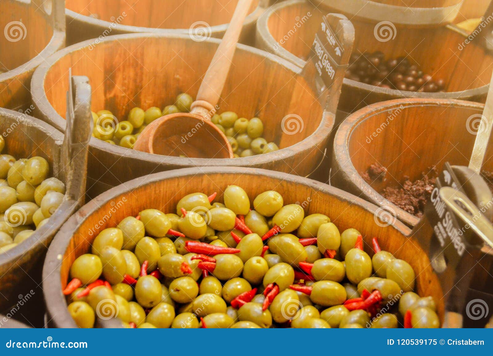 Varianten van olijven. Diverse ingelegde en gevulde olijven worden aangeboden voor verkoop in houten emmers