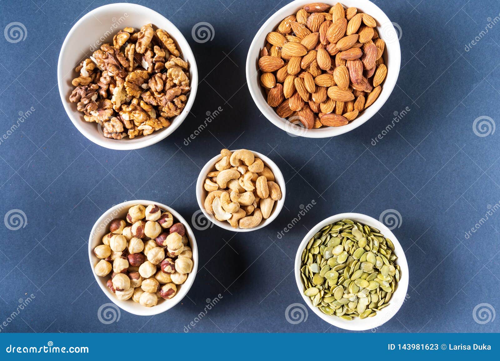 variation of nuts in bowls on gray background