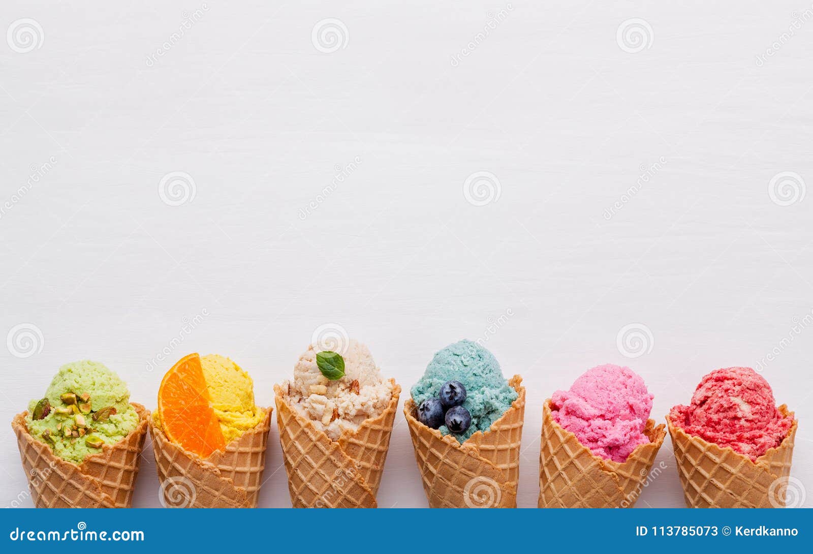 various of ice cream flavor in cones blueberry ,strawberry ,pistachio ,almond ,orange and cherry setup on white wooden background