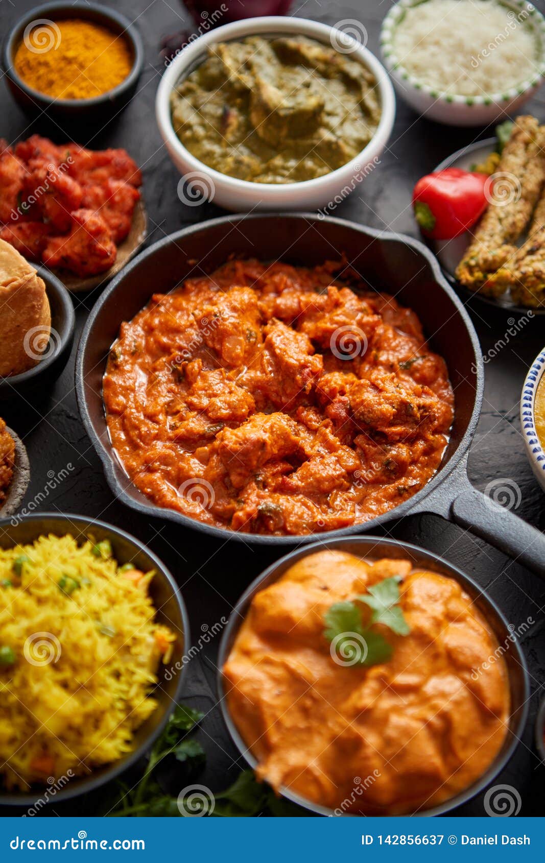 various indian dishes on a table. spicy chicken tikka masala in iron pan