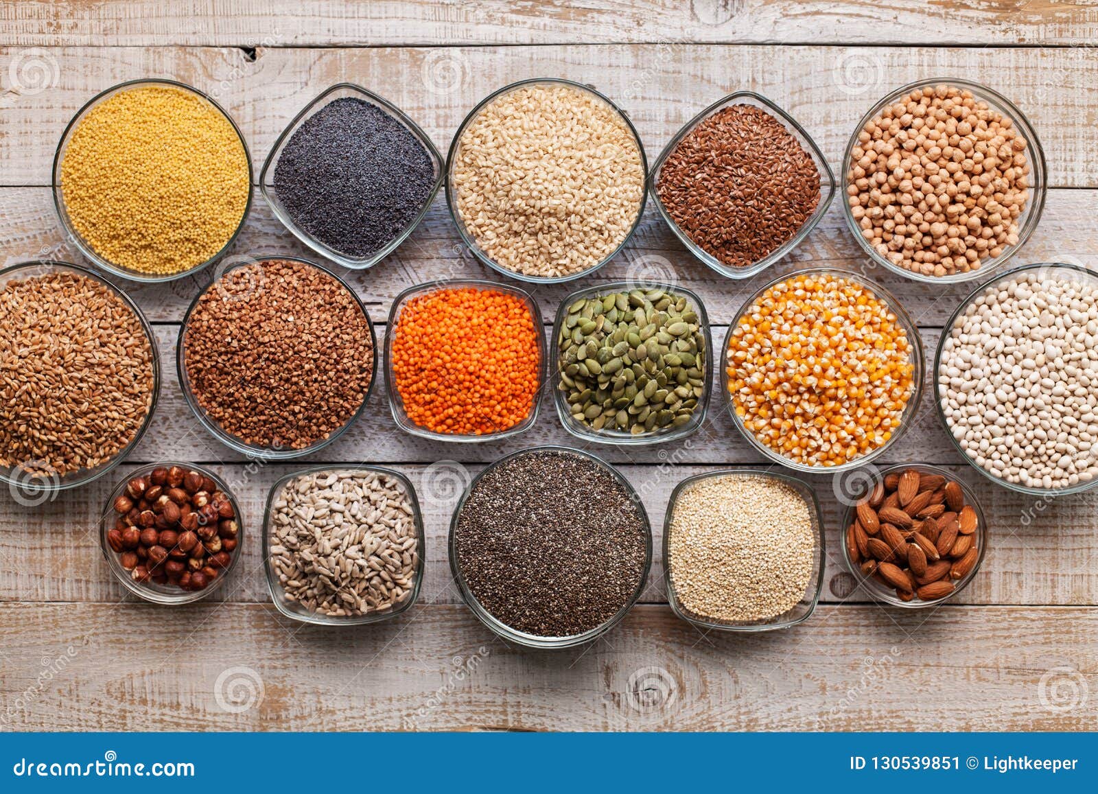 various seeds, grains and nuts on old table - in bowls, top view