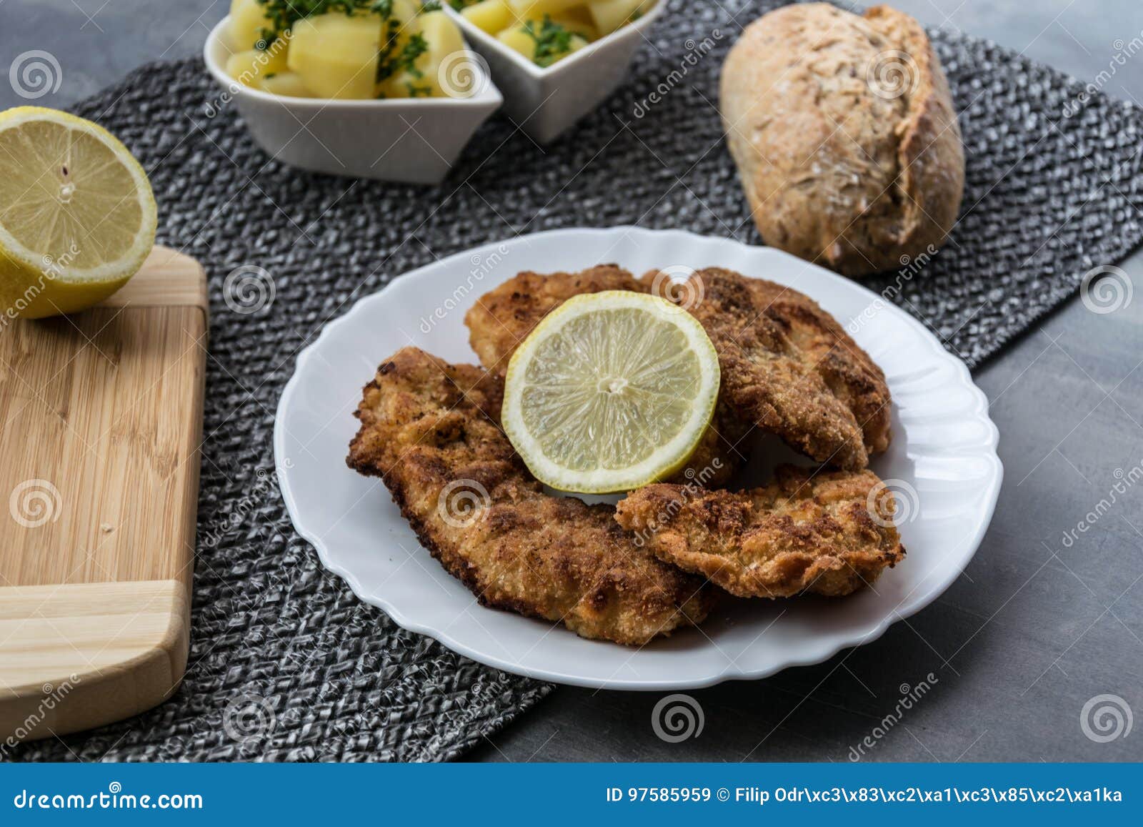 Varkensvleesschnitzel met citroen en gedobbelde aardappels. Varkensvleeslapje vlees op reuzel met peterselieaardappels en gebakje dat wordt gebraden