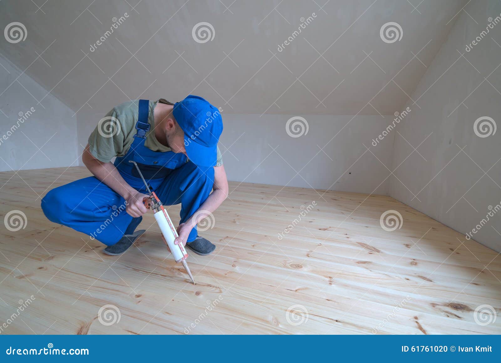 Wooden floor varnished. Worker with silicon gun.