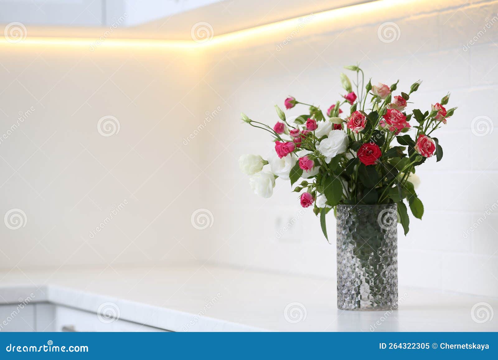 Vase with Beautiful Flowers on White Countertop in Kitchen, Space for