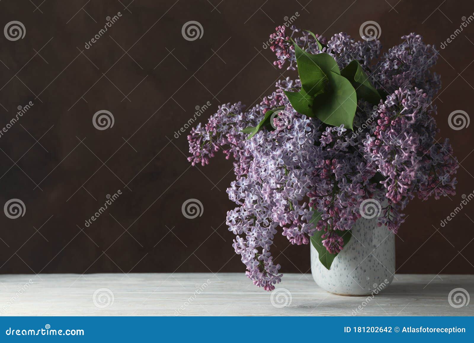 Vase of Lilac Flowers on Brown Background Space for Text Stock Photo