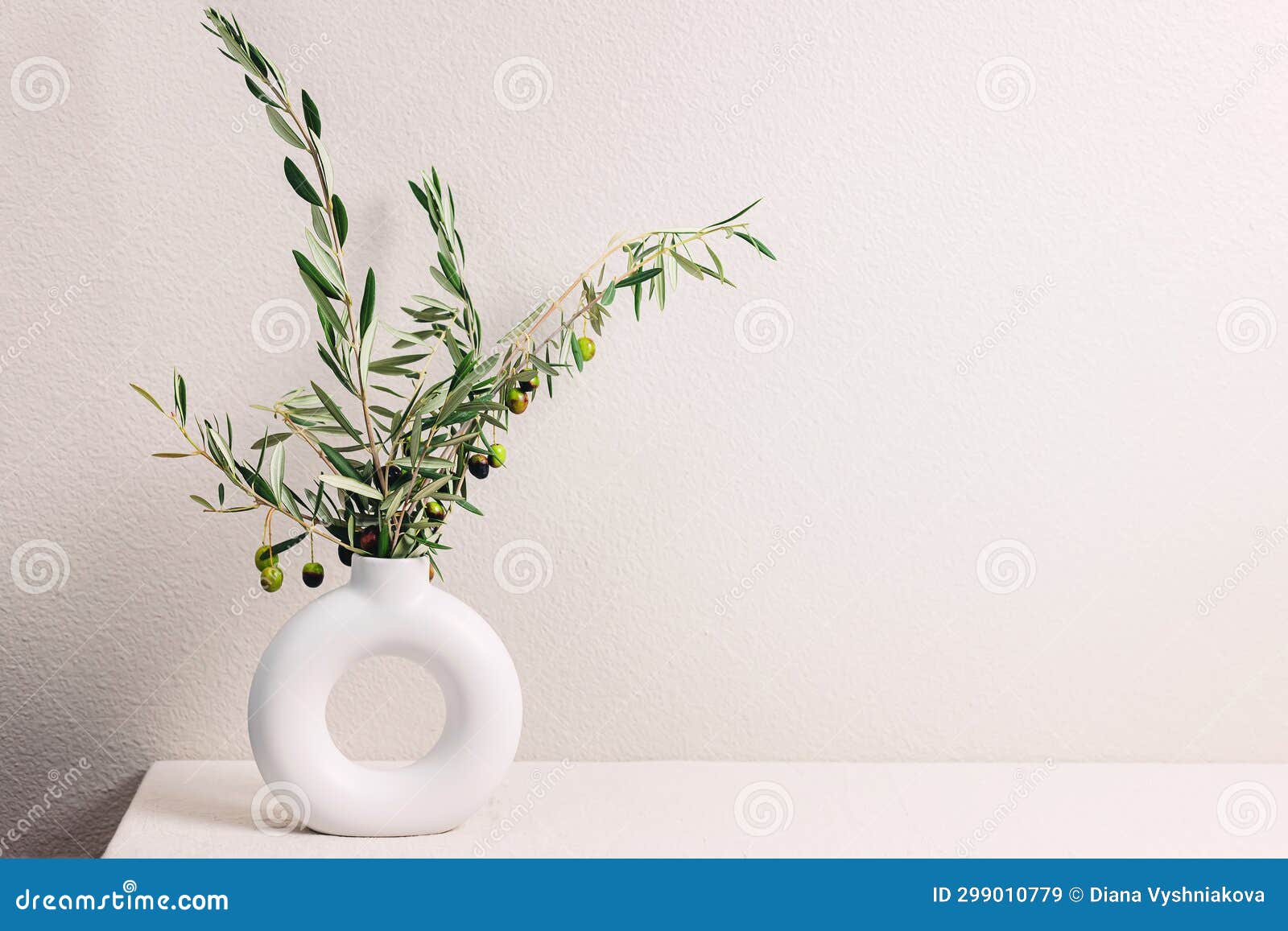 Vase with Olive Tree Branches Over the Light Gray Wall Stock Image