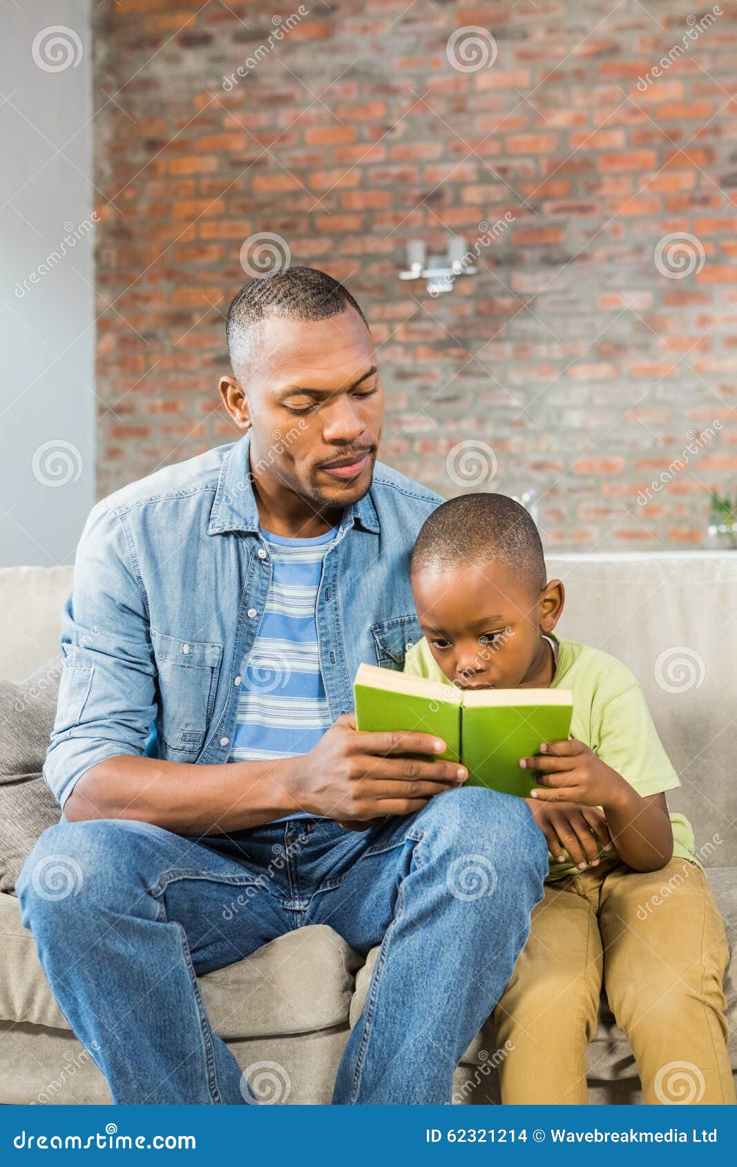 Vater- Und Sohnlesung Auf Der Couch Stockfoto - Bild von fußboden