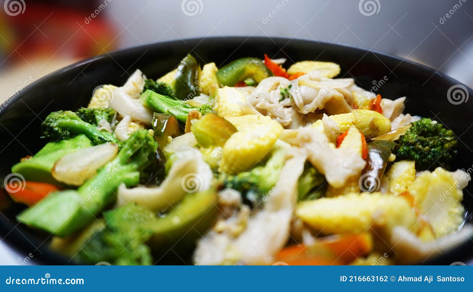 vegetable capcay young corn with mushrooms and also peppers seen up close squatted black color with kater striped blur
