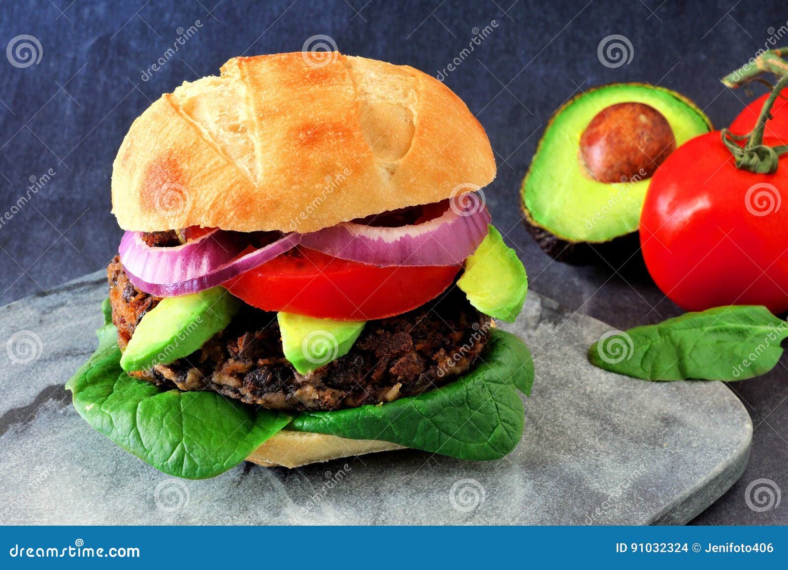 veggie burger with avocado and spinach on a dark background