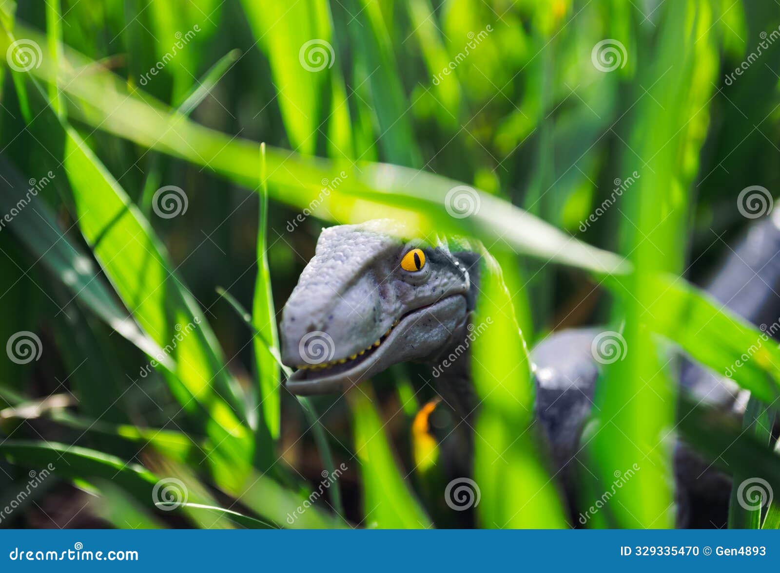 velociraptor dinosaur toy in the middle of lush green grass