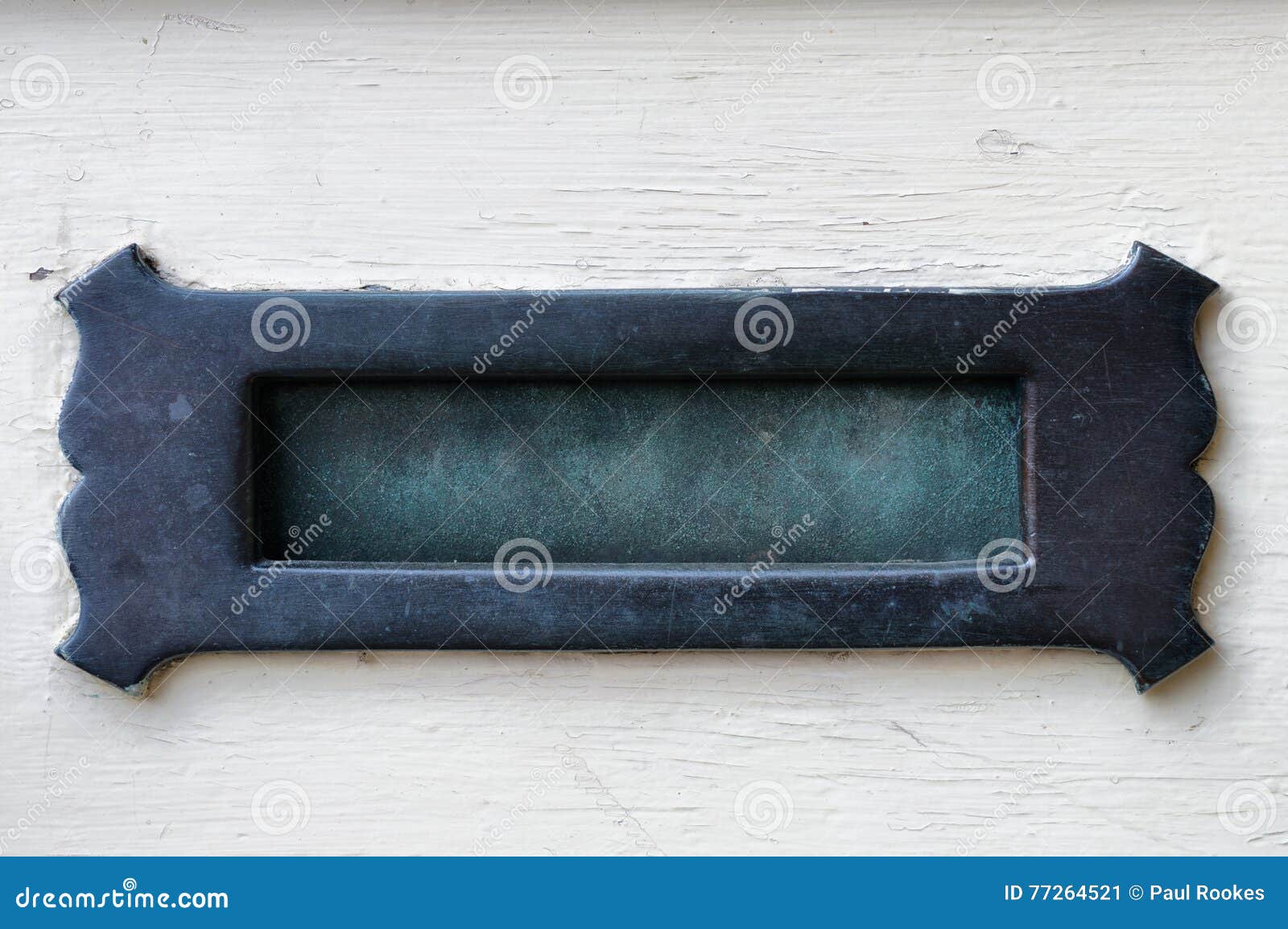 verdigris brass letter box in an off white door.