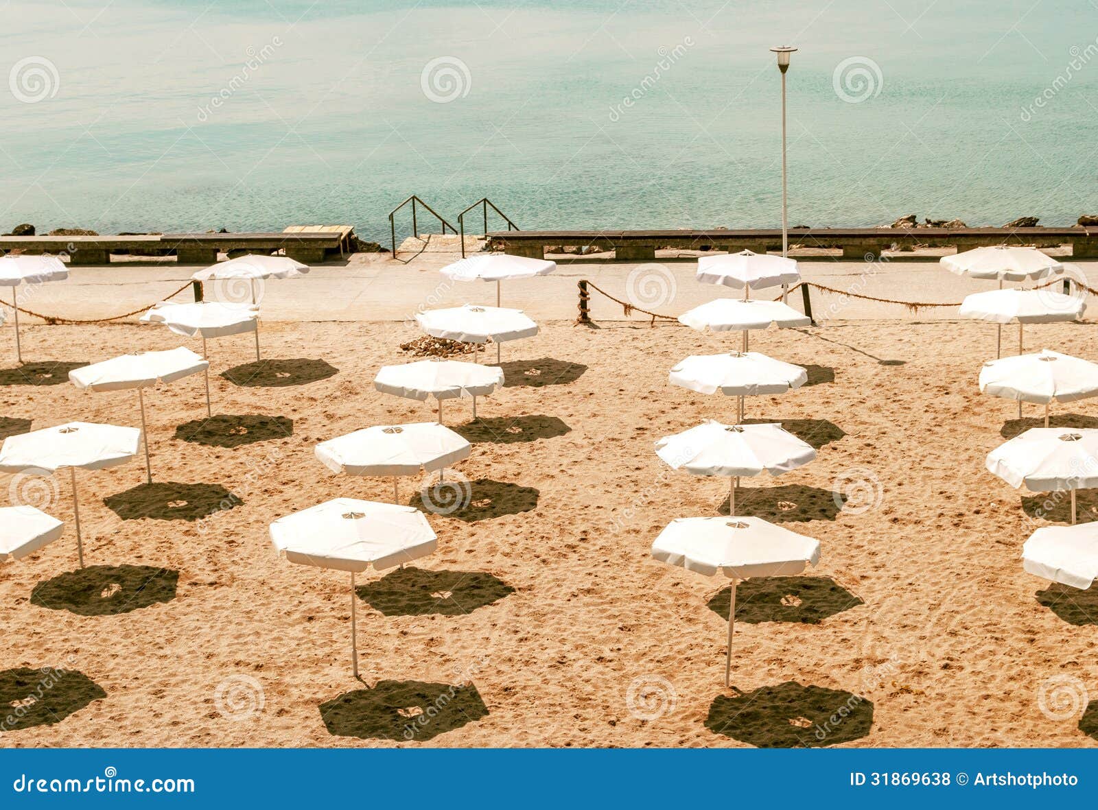 Verlaten strand met witte paraplu's. Beeld van een verlaten strand in een zonnige dag