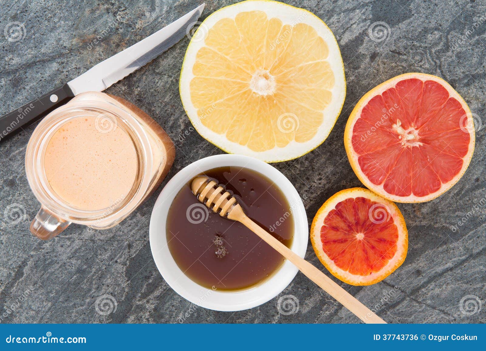 Vers die grapefruit en sap met honing wordt gediend. De heerlijke verfrissende ontbijtdrank van vers gedrukte grapefruit juice diende met honing en grapefruit de helften voor een gezond ontbijt, luchtmening op steencountertop