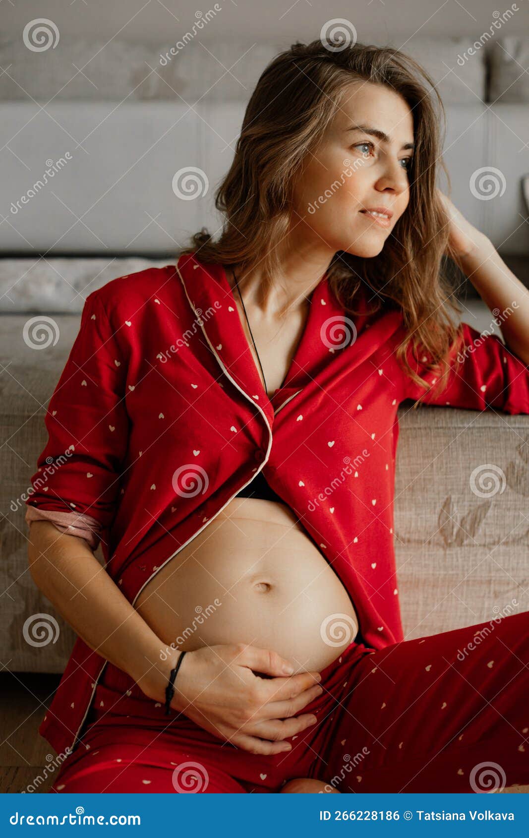 Vertical Calm, Pensive Pregnant Blond Woman Sitting and Hold Naked Abdomen,  Wear Red Loose Pajamas, Resting, Sit Indoors Stock Photo - Image of parent,  child: 266228186