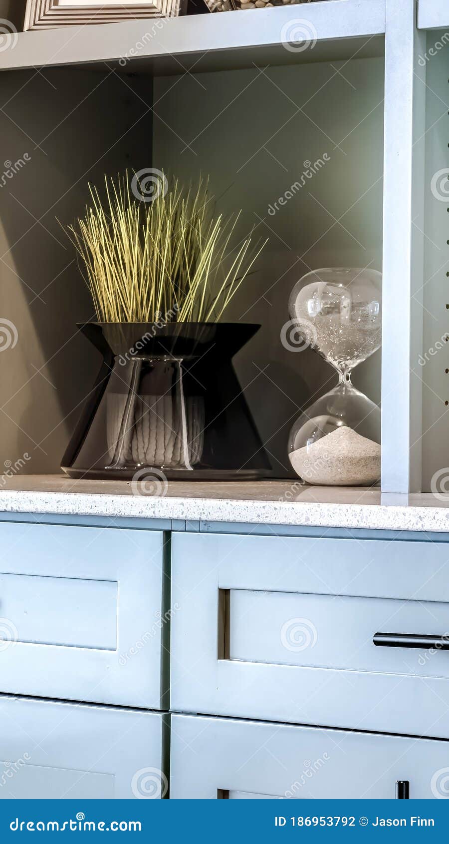 vertical close up of cabinet with ornamental plants and hourglass on the display shelves