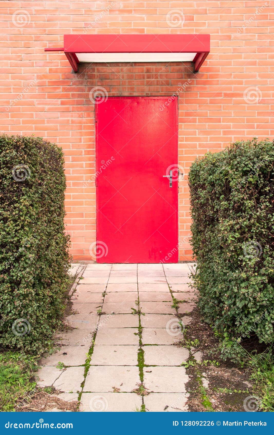 vertical image. red door surrounded by orange brick wall.