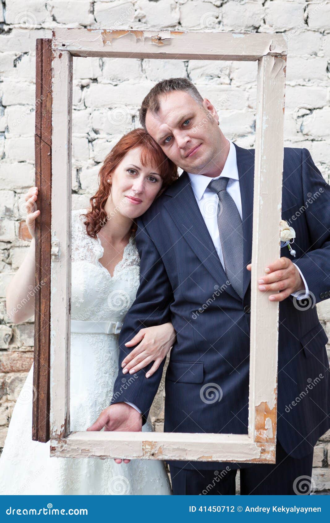 Vertical Photo of Bride and Groom Looking through Portrait Frame Stock