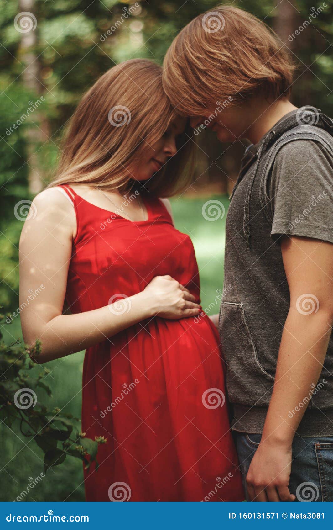 Vertical Photo. a Happy Married Couple Husband Hugs a Beautiful Adult Pregnant Wife. Walks in a Park picture