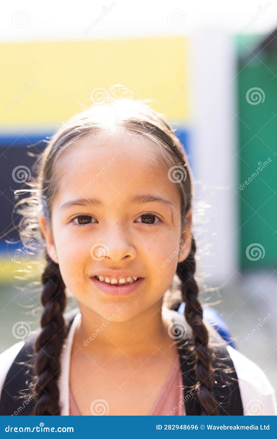vertical portrait of smiling cauasian ary schoolgirl in school playground, copy space