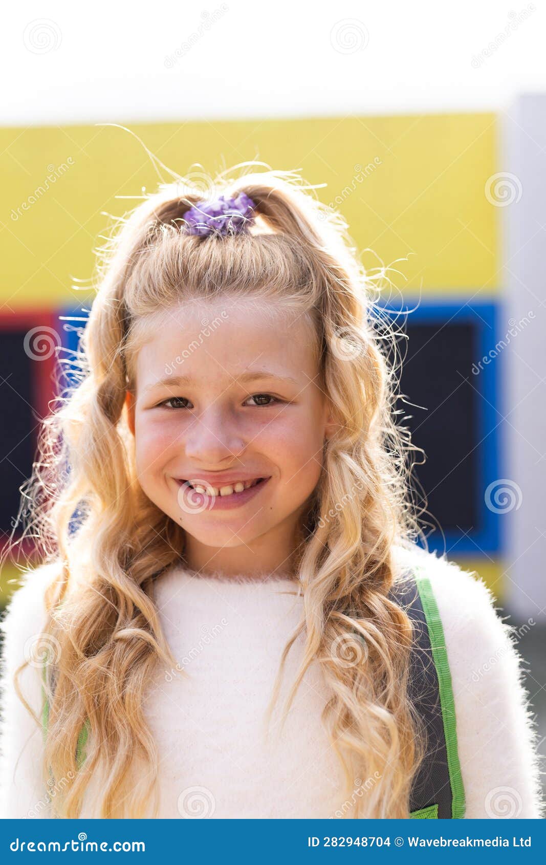 vertical portrait of smiling cauasian ary schoolgirl in school playground, copy space