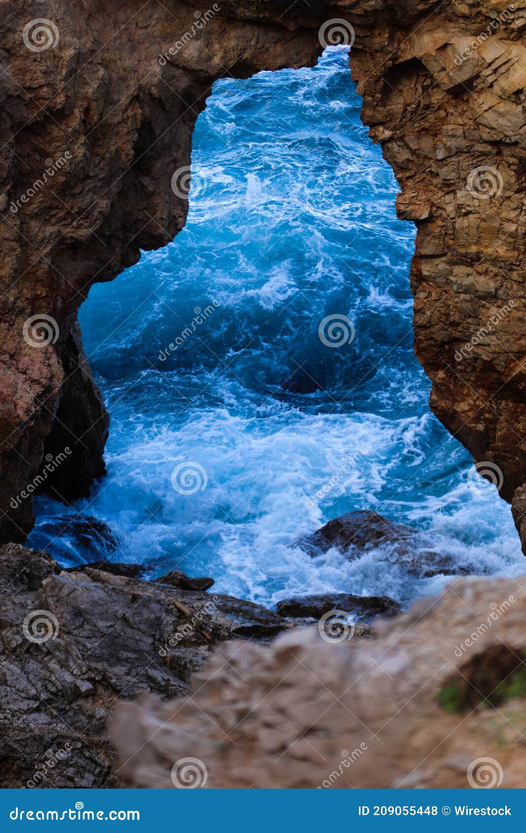 vertical shot of the blue ocean opening from a rock view in menorca. islas baleares. spain.