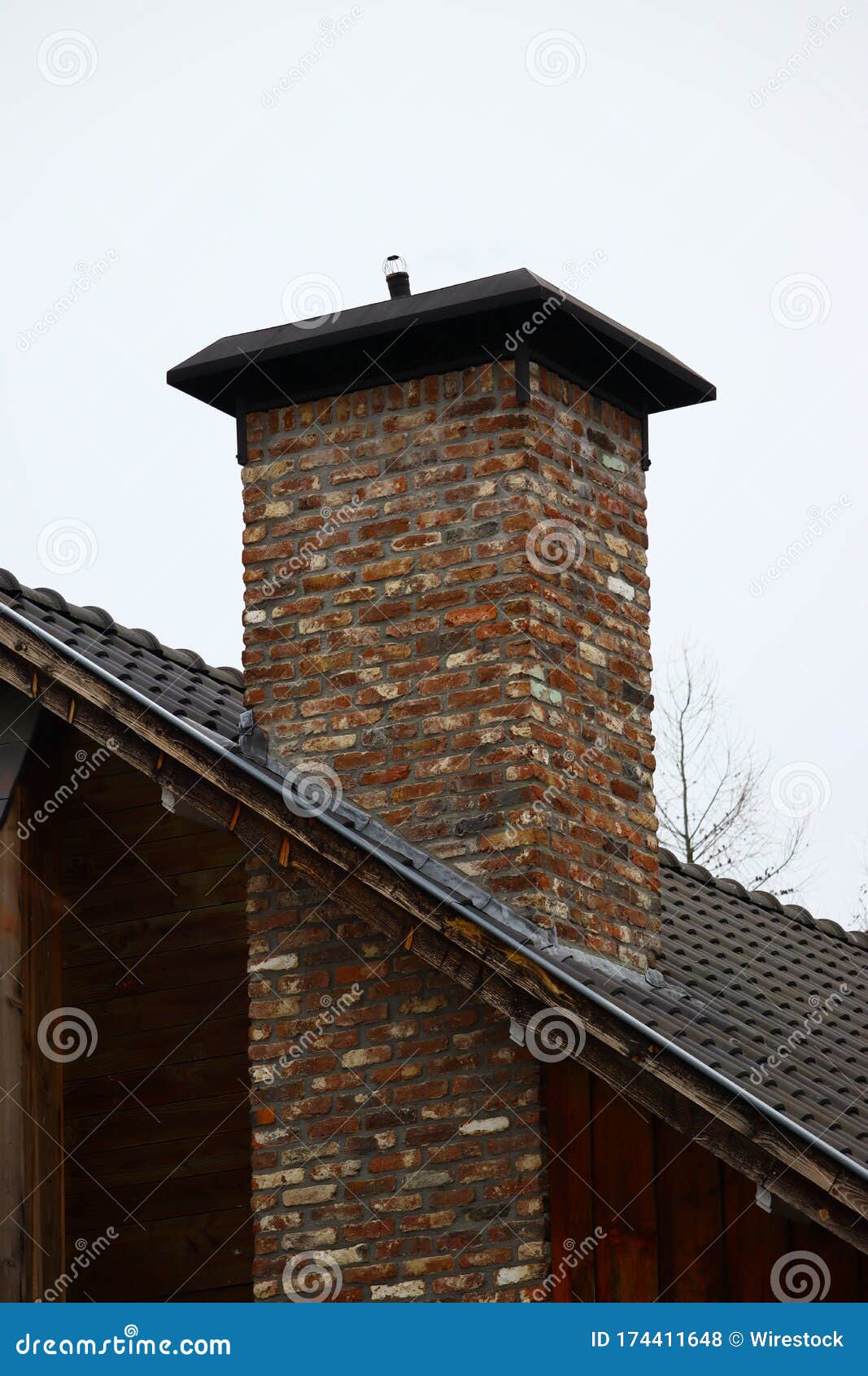 vertical shot of a brick chimney with a cloudy sky in the background