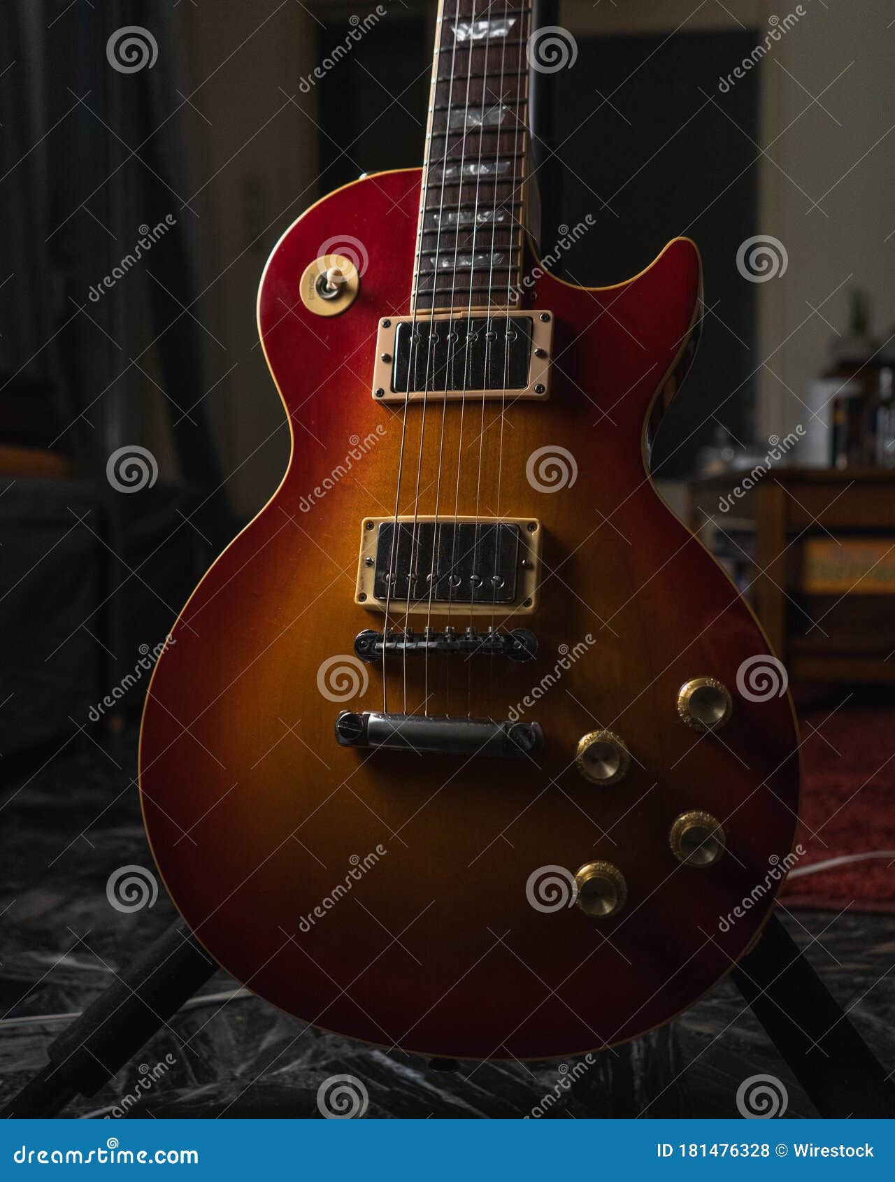 Vertical Shot of a Brown Acoustic Guitar on the Ground Stock Photo