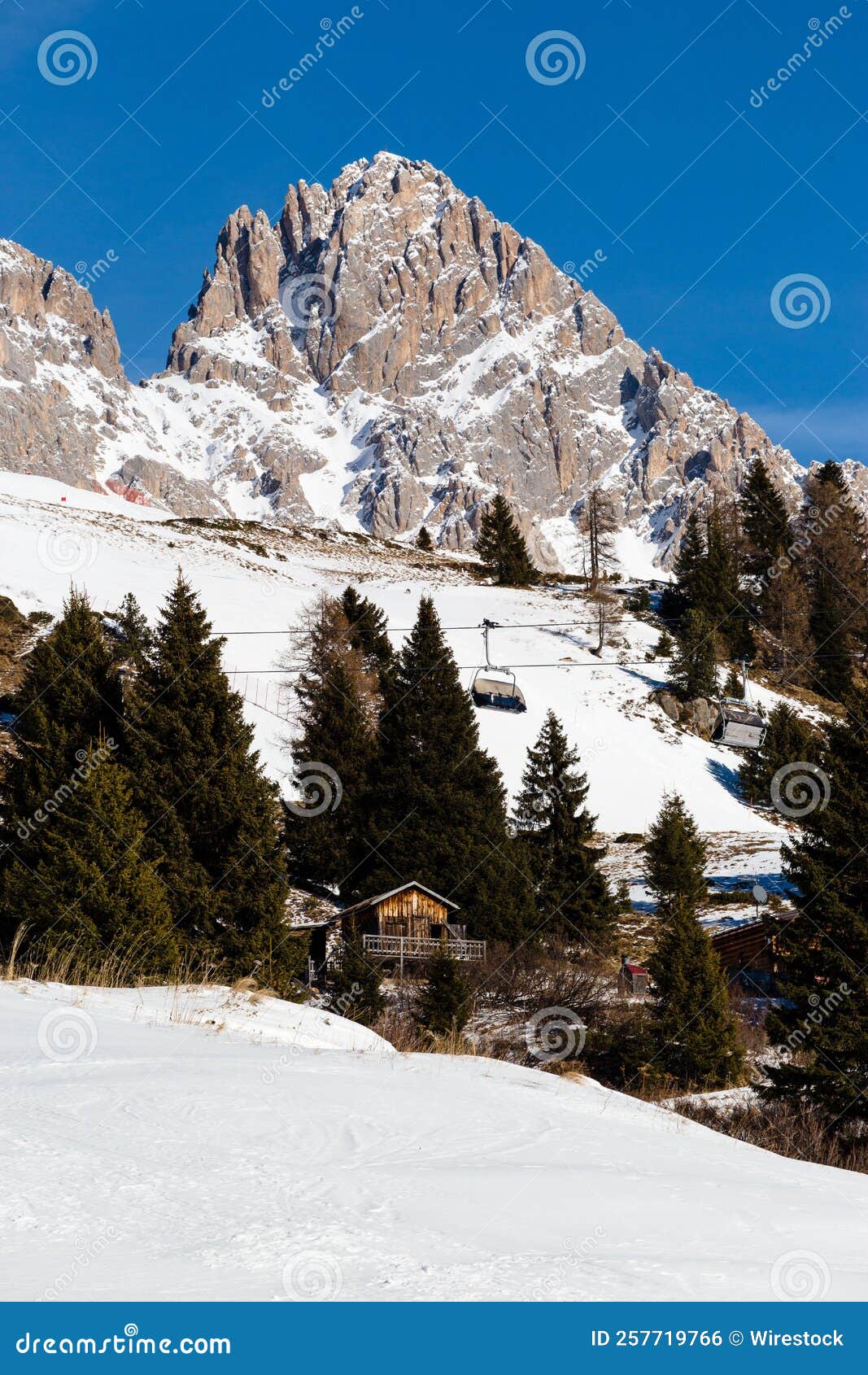 vertical shot of the cima uomo mountain in the dolomites with ski lift and log cabin