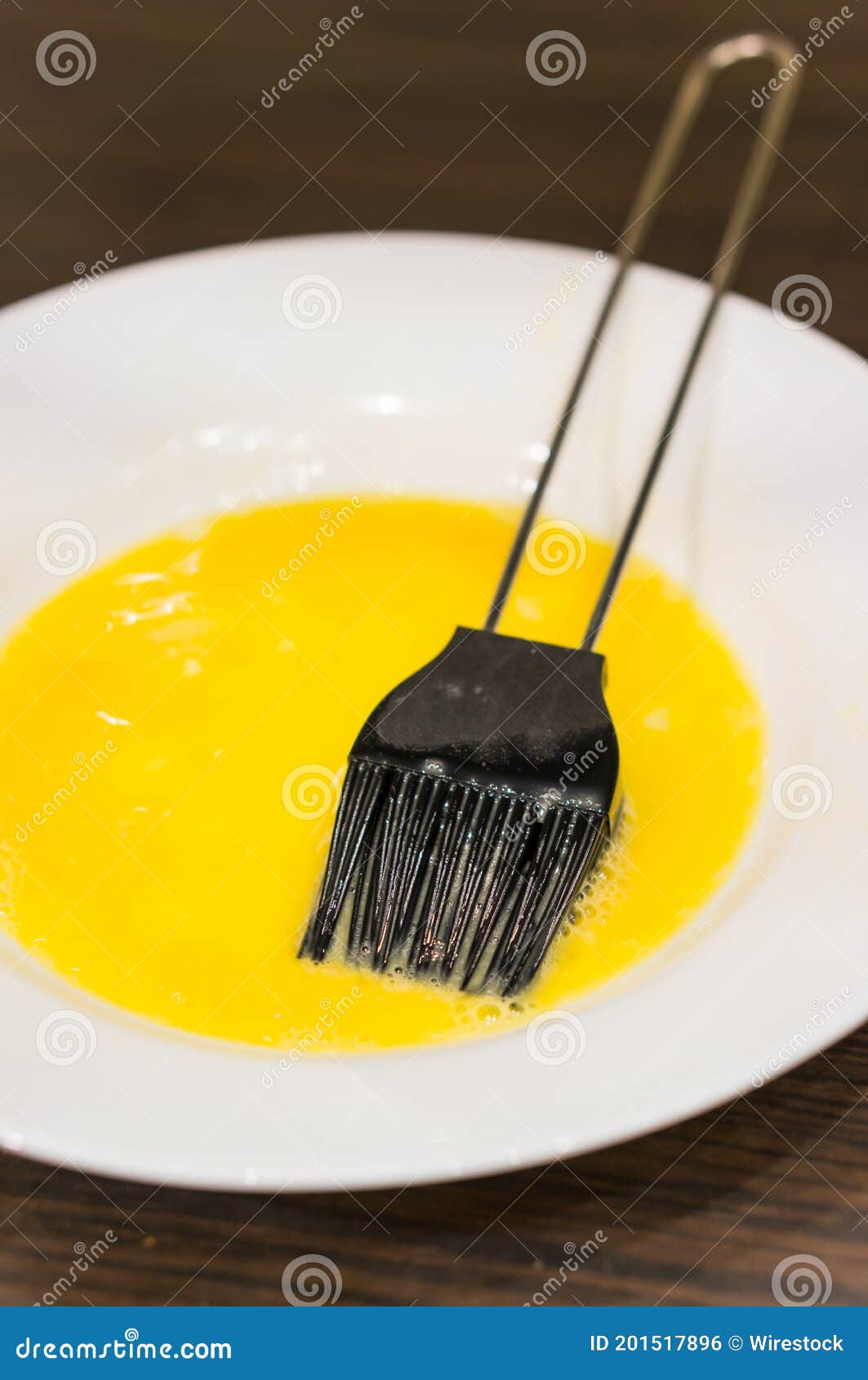 Vertical Shot of an Egg Wash in a Plate with Black Pastry Brush