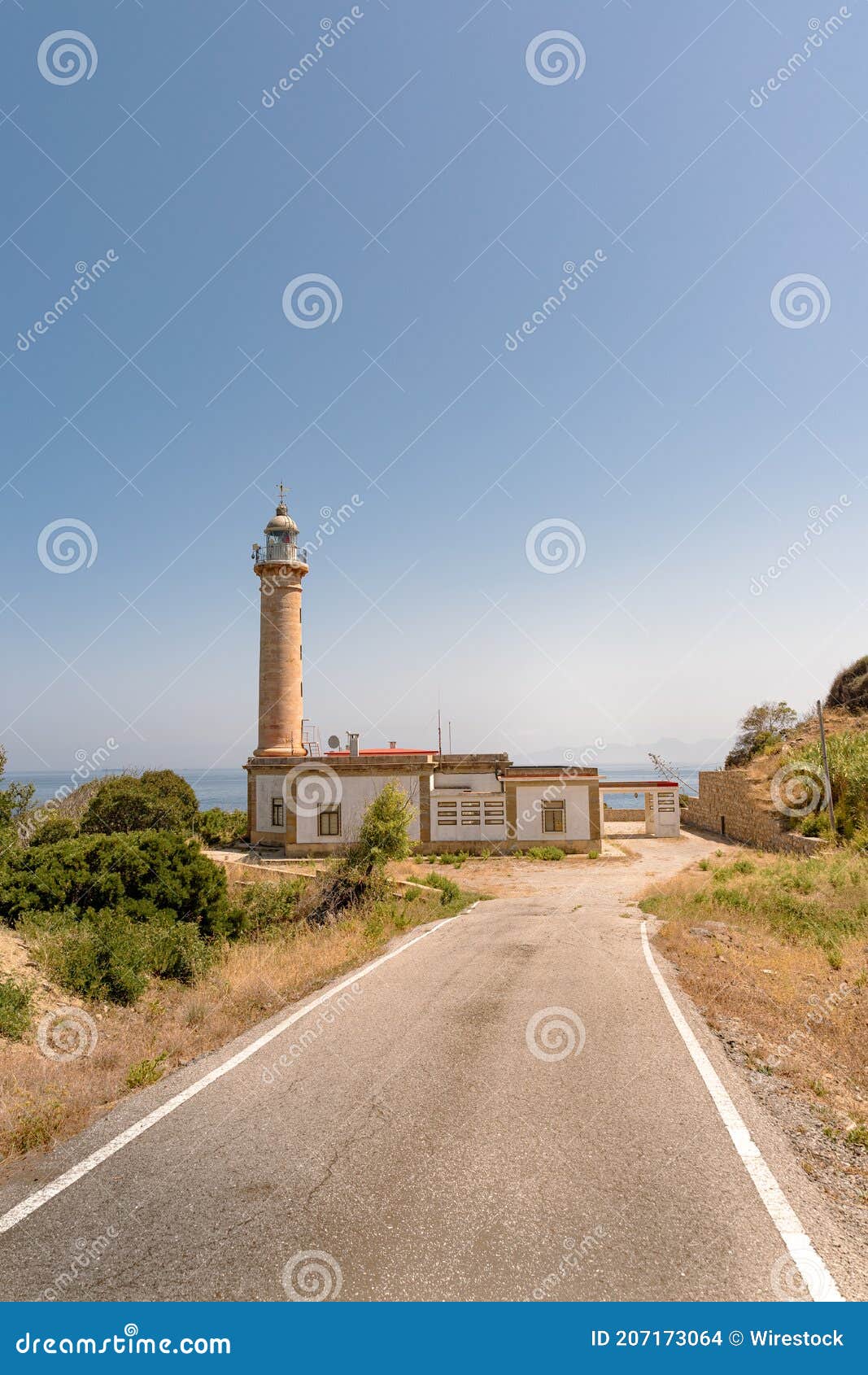 vertical shot of the faro punta carnero lighthouse near a road in spain