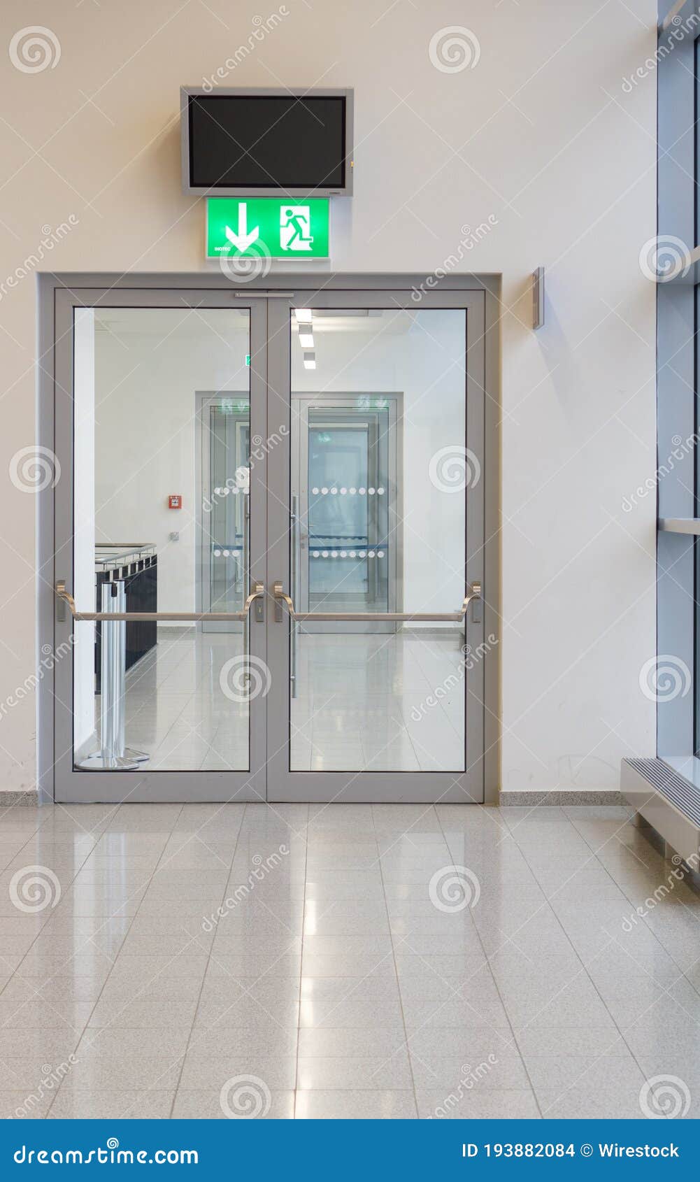 Vertical Shot of a Glass Door and an Emergency Exit Sign Above the Door