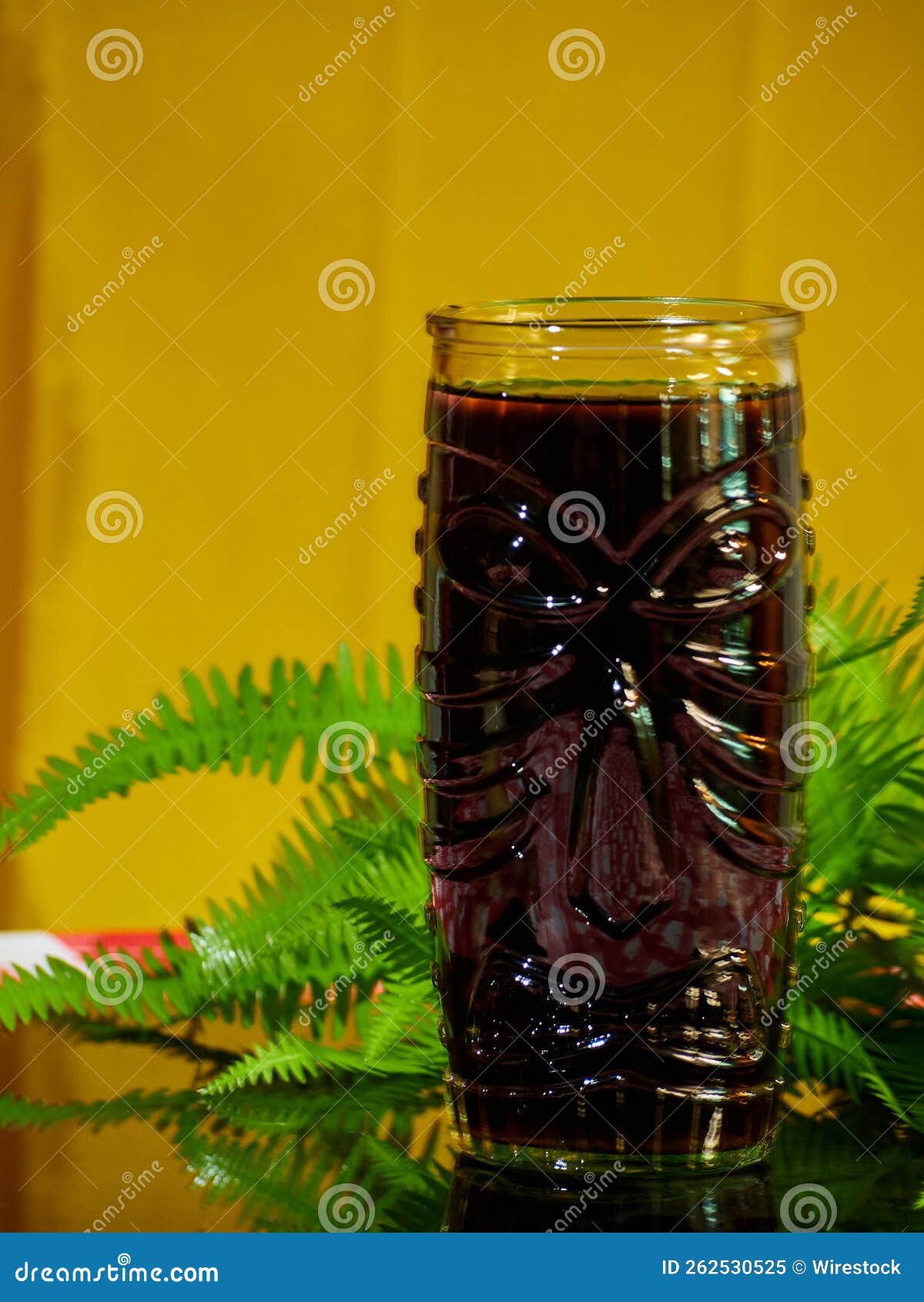 Vertical Shot of a Glass with Juice on a Table with Green Plants Stock
