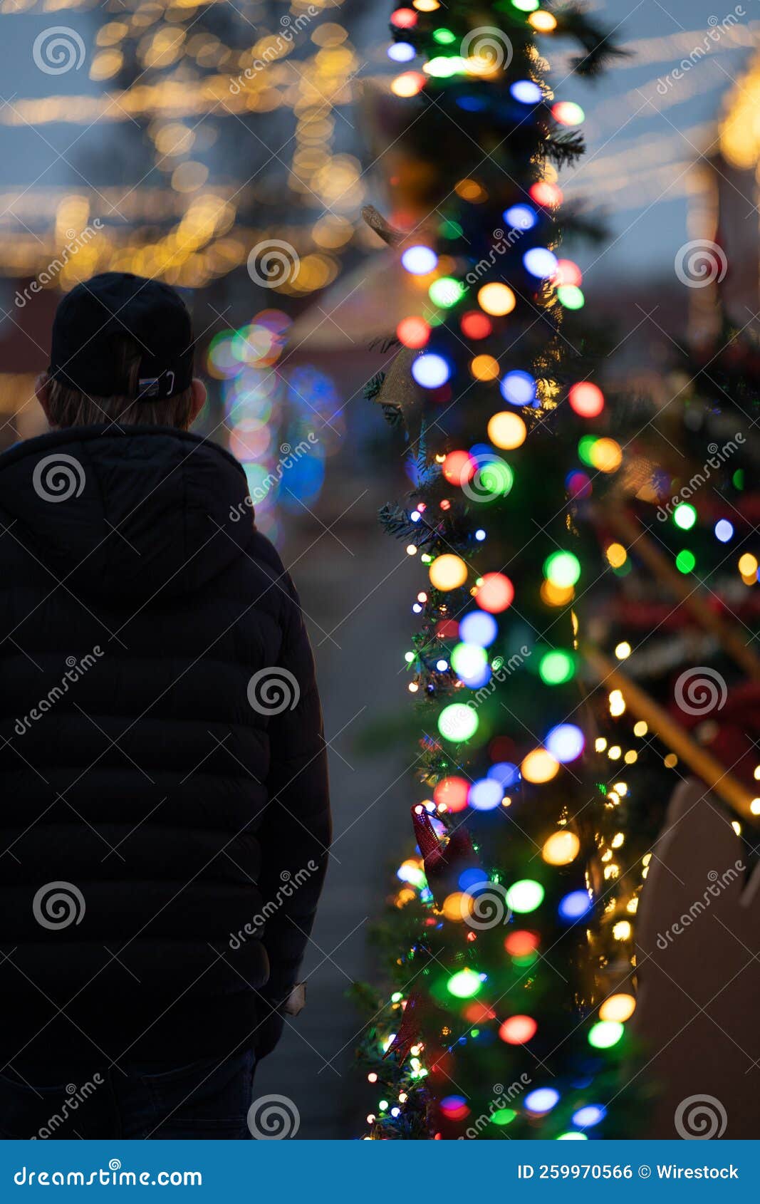 Vertical Shot of Glowing Christmas Lights on a Pole with a Person ...