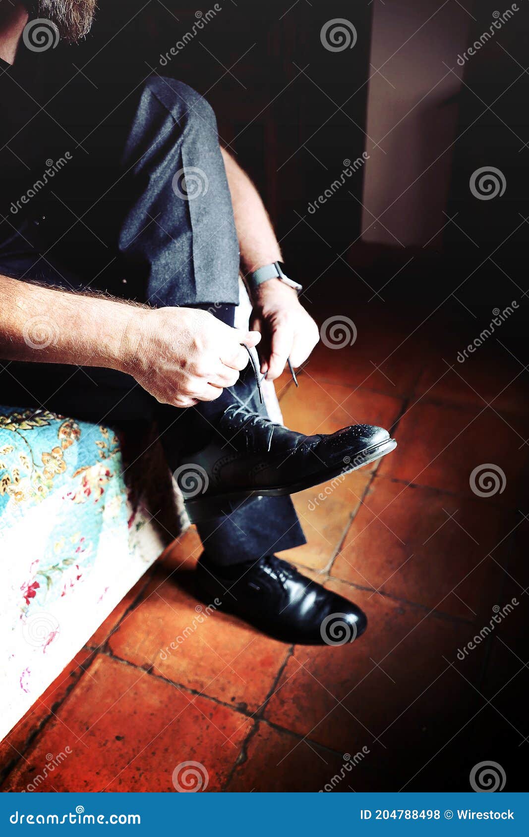 vertical shot of a groom wearing his shoes - wedding details