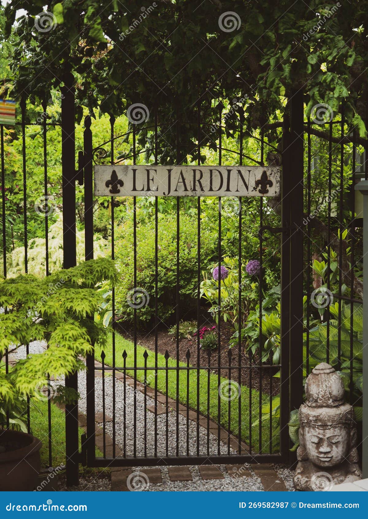 vertical shot of a metal gate with the french words 'le jardin' - translation: the garden