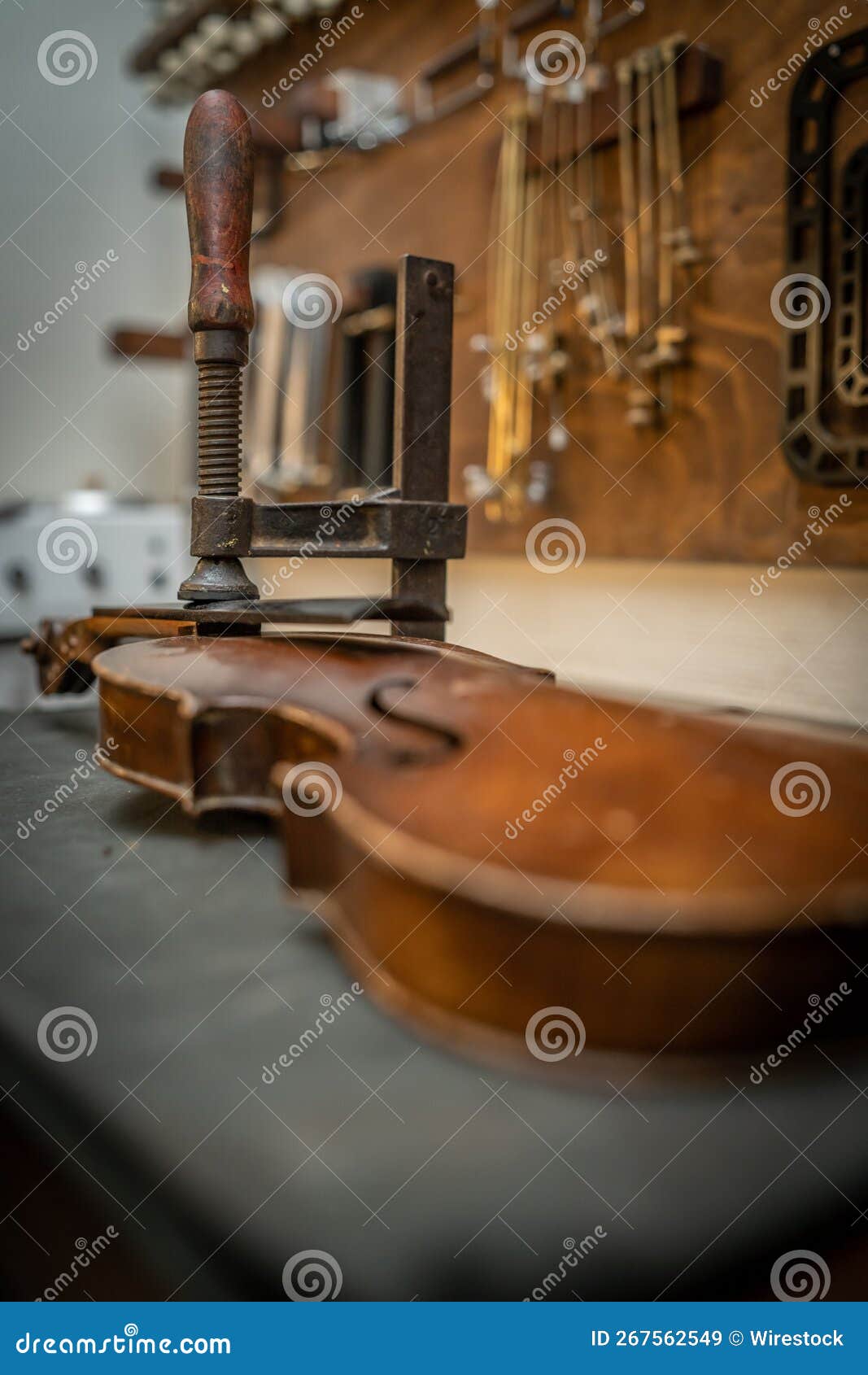 vertical shot of a violin in the process of luthiery with restoration tools hang on the background