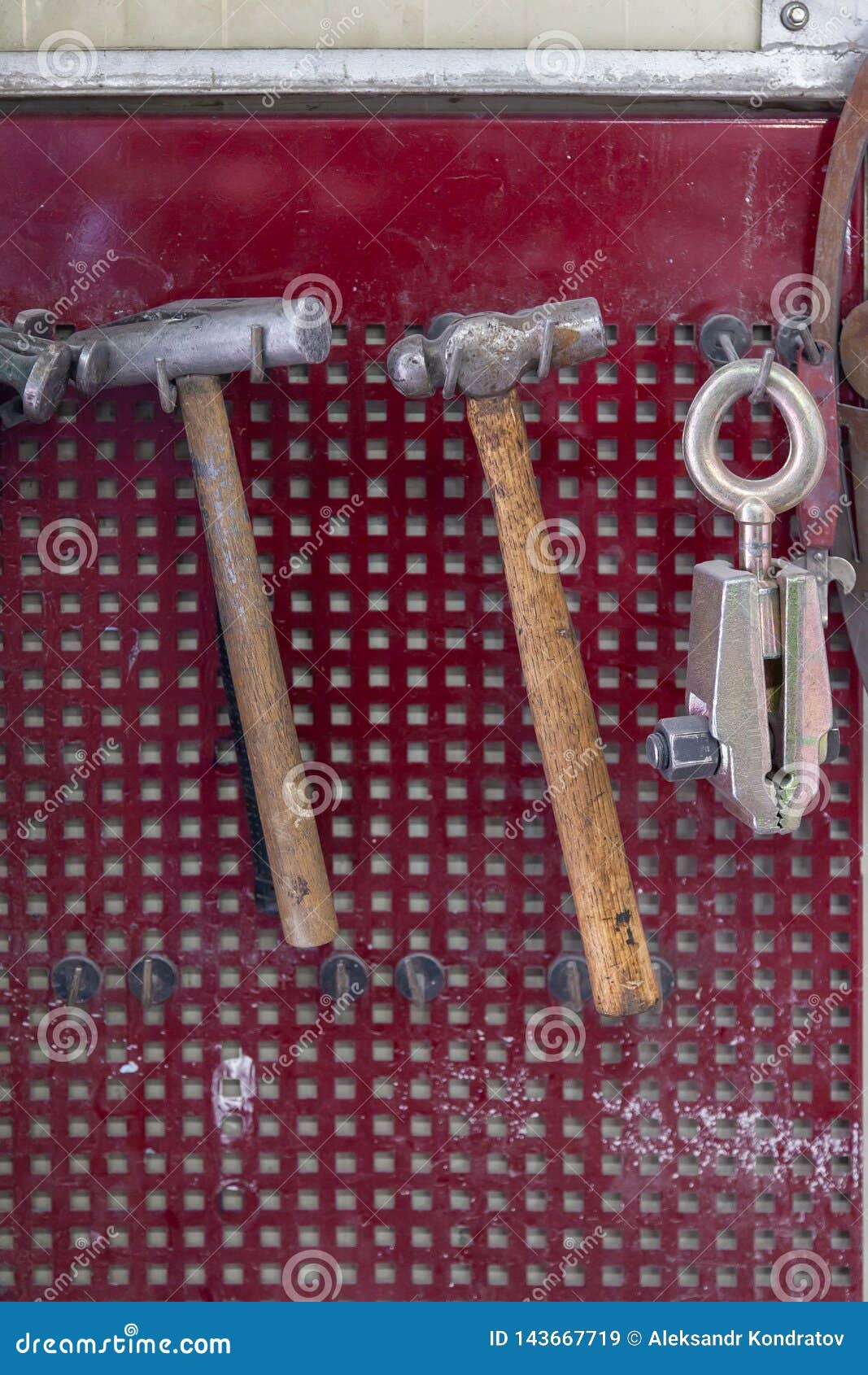 Vertical View of Two Old Hammers with a Brown Wooden Handle and a Clamp