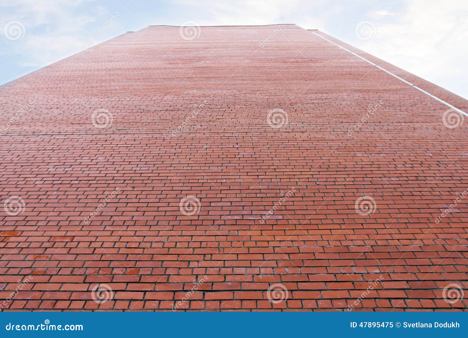 very high wall of red brick building and cloudy sky