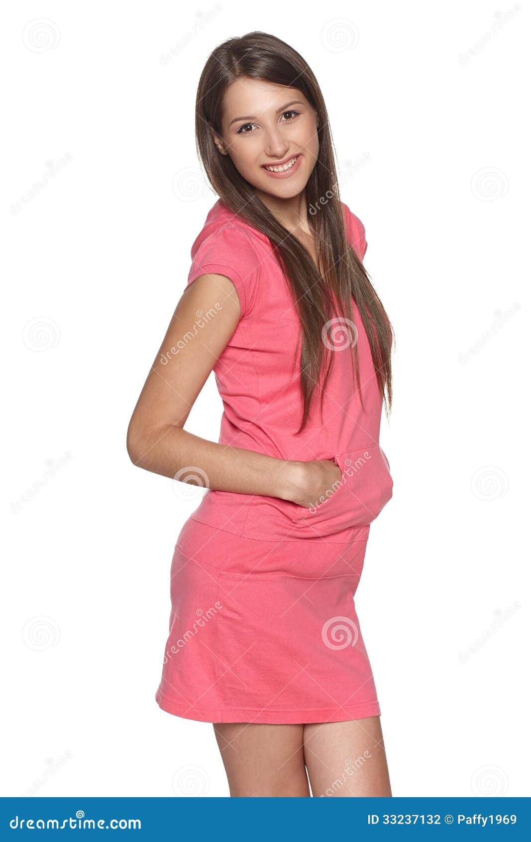 Vestido femenino feliz del rosa del estilo del deporte que lleva que se coloca con las manos en el bolsillo, aislado en el fondo blanco