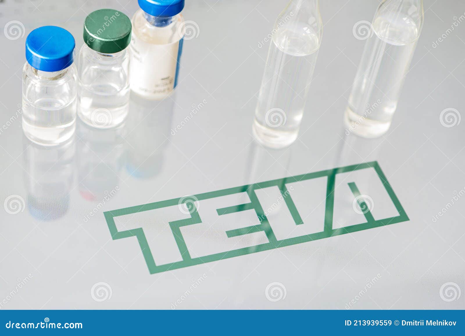 Vials of Liquid on a White Table and the Logo of a Large Pharmaceutical