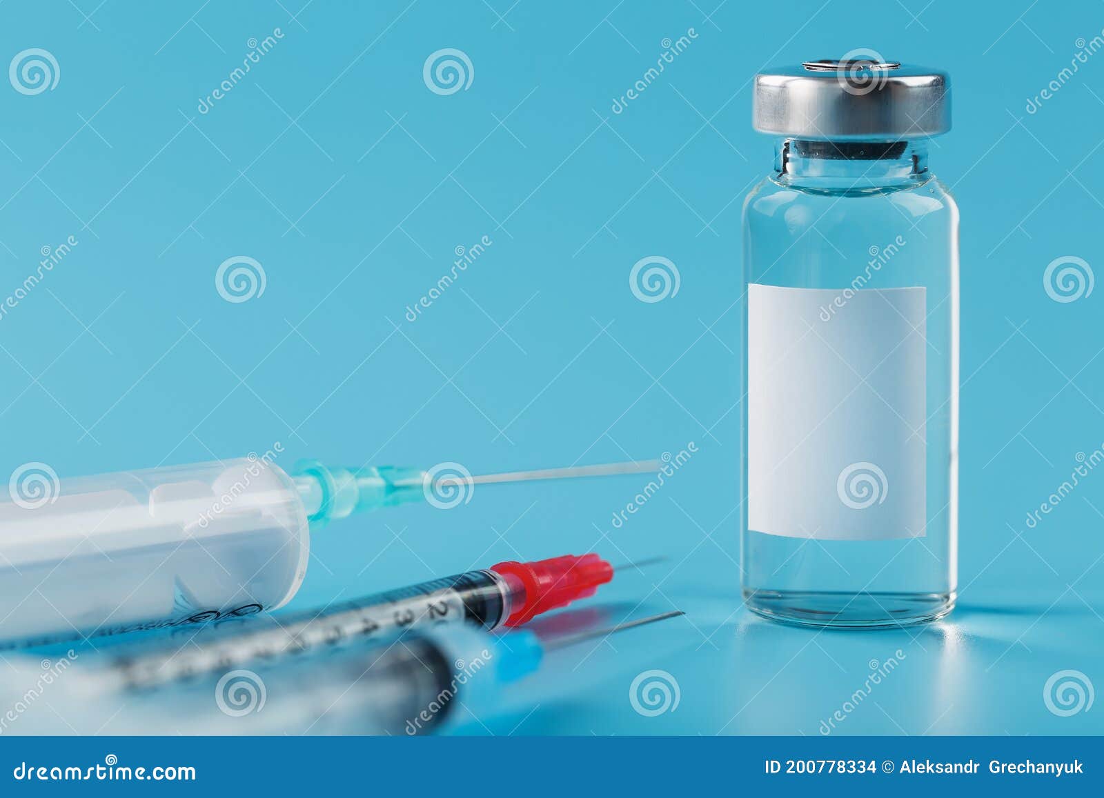 vials of vaccine and syringes in a row on a blue background close-up