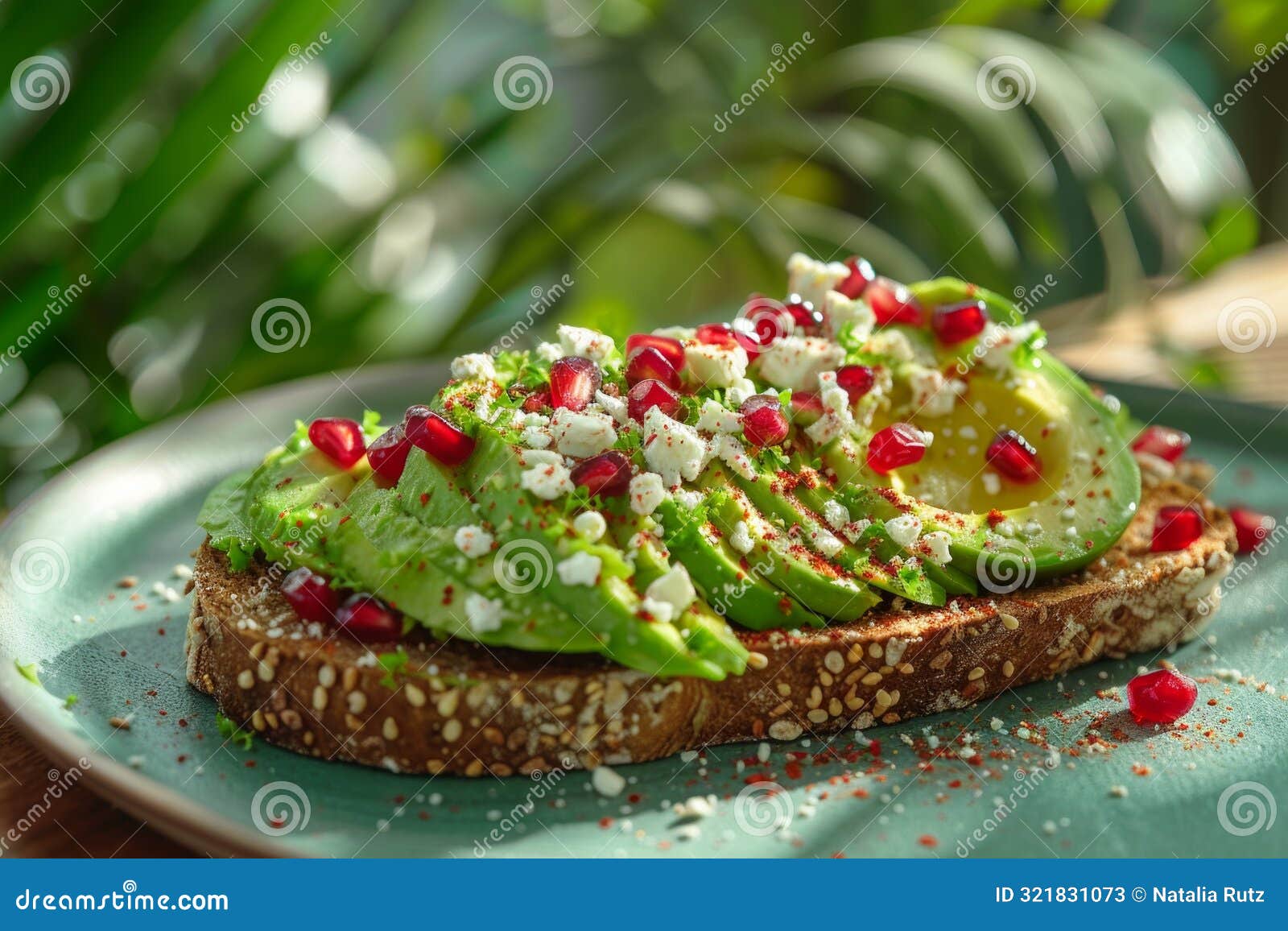 vibrant avocado toast with smashed avocado on rye bread, topped with pomegranate seeds, feta cheese, and chili flakes