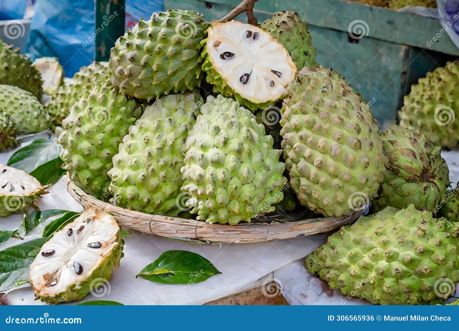 a vibrant display of fresh soursops, one cut open revealing the juicy interior, at an outdoor market