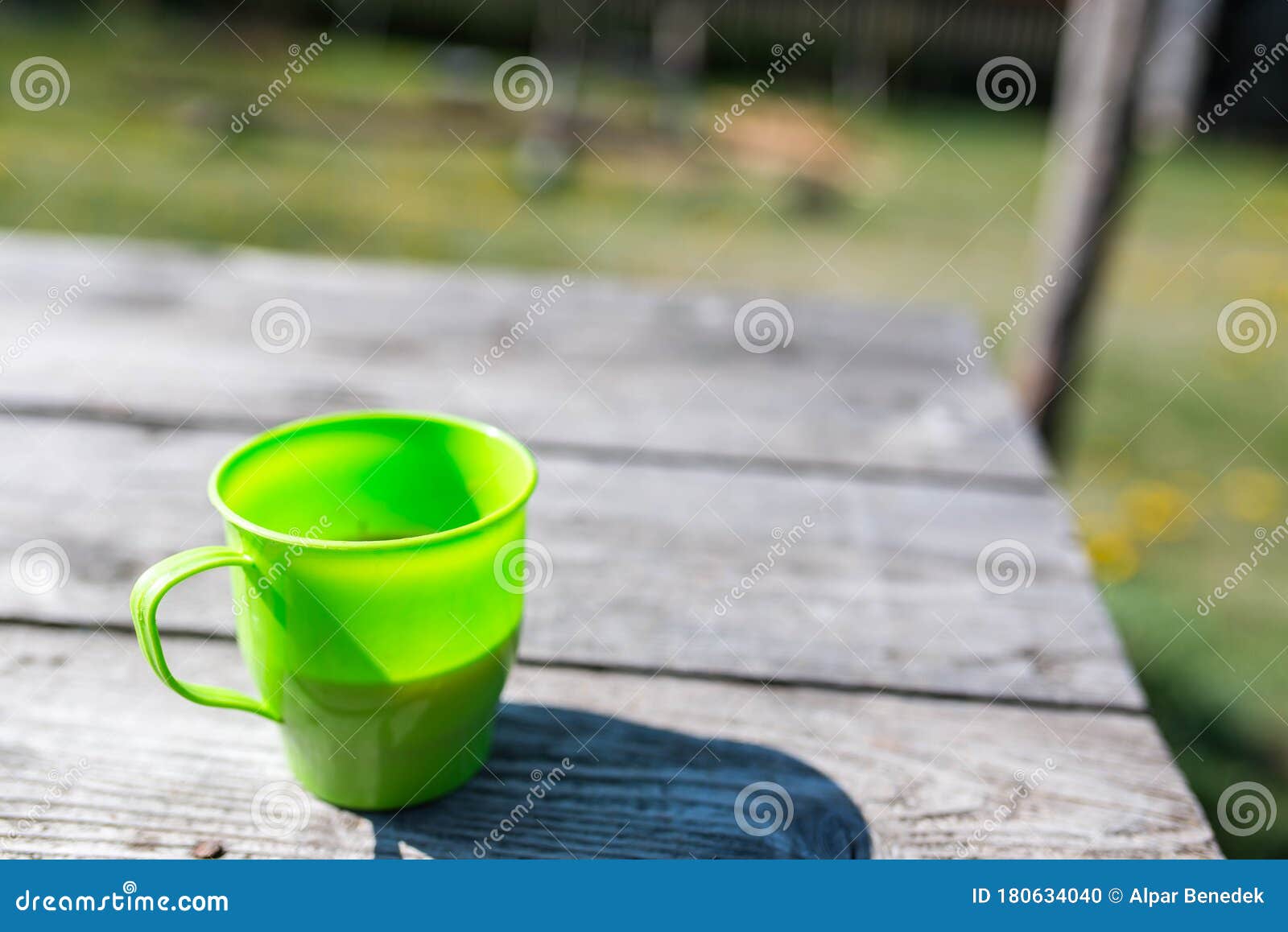 Vibrant Green Plastic Cup with Shadow Filled with Coffee on Aged Pine